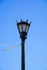 Fototapeta na wymiar Black ornate street light set against bright blue sky