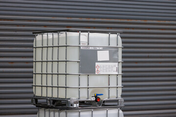 white ibc containers with steel shutter door of factory background, white plastic chemical tanks.
