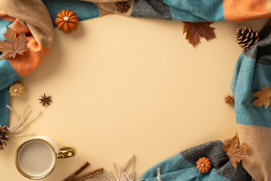 Warm autumn vibes captured in top view shot: cup of steaming coffee, cozy plaid, small pumpkins, yellow maple leaves, pine cones, cinnamon sticks, anise on pastel beige backdrop. Space for text or ad
