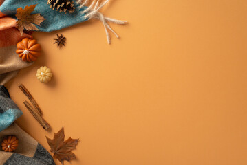 Welcome autumn vibes. Top view of warm blanket, miniature pumpkins, golden leaves, pine cone, cinnamon sticks, and star anise on an orange backdrop. Perfect for text or advertising