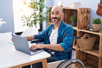 Young hispanic man sitting on wheelchair studying at home