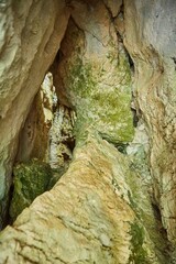 Dark cave view from inside with a lumen. Stalactites and stalagmites inside the stone grotto. Colorful stones in the cave.