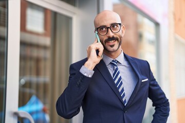 Young hispanic man executive smiling confident talking on smartphone at street