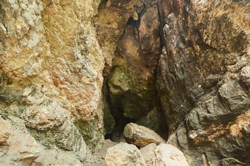 Dark cave view from inside with a lumen. Stalactites and stalagmites inside the stone grotto. Colorful stones in the cave.