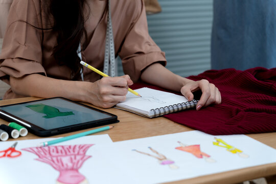 young woman designer drawing clothes using electronic  pencil