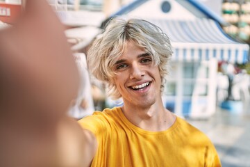 Young blond man smiling confident making selfie by camera at street