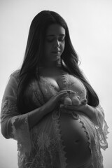 Young pregnant woman tenderly looks at the booties of her future baby.