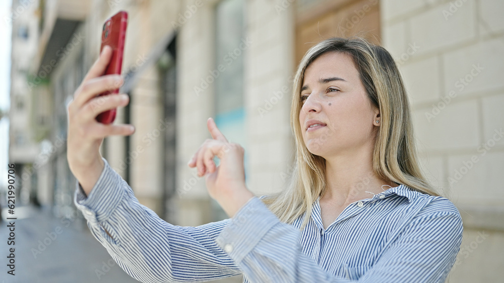 Poster Young blonde woman making selfie by the smartphone at street