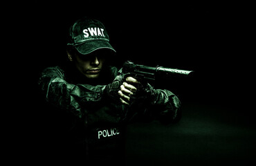 Spec ops police officer SWAT in black uniform aiming pistol with silencer, studio shot, half length