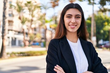 Young beautiful hispanic woman standing with arms crossed gesture at street