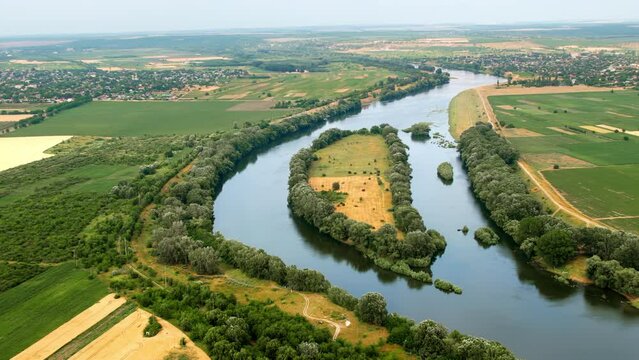 Aerial drone view of nature in Moldova. Dniester river with lush trees along it, villages in the distance and fields around