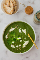 Healthy breakfasts, green broccoli and spinach cream soup with sunflower seeds and yogurt, buckwheat bread, top view