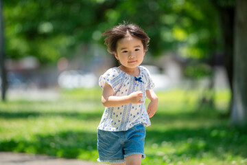 新緑の公園で遊ぶ3歳の女の子