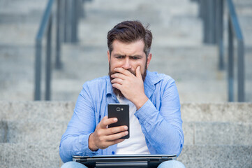 Disappointed man lost bet. Upset man checking up betting results in mobile phone. Betting online