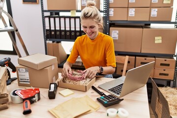 Young blonde woman ecommerce business worker packing diadem on cardboard box at office