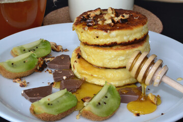 on a plate are cut cheese pancakes, chocolate and honey
