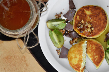 cut cheese pancakes and a jar of honey lie on a white plate