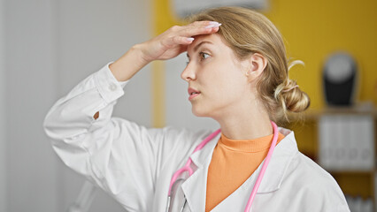 Young blonde woman doctor standing with serious expression stressed at clinic