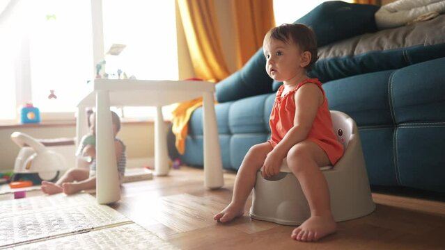 baby sitting on the potty. Toddler baby girl goes to the toilet sits on the potty next to the sofa indoors. happy family kid dream concept. baby learns to lifestyle go to the toilet on the potty
