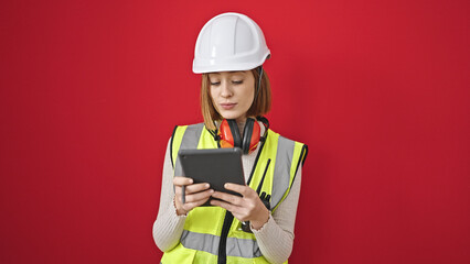 Young blonde woman architect drawing on touchpad with serious expression over isolated red background
