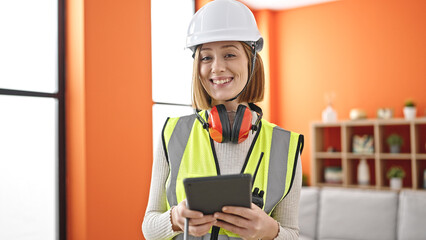 Young blonde woman architect smiling confident using touchpad at home