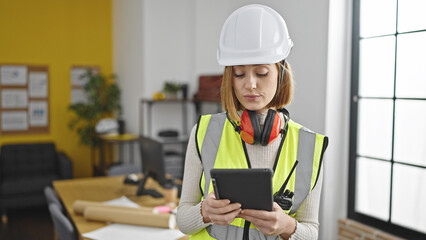 Young blonde woman architect using touchpad with serious expression at office