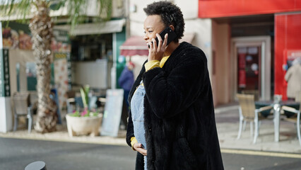 Young pregnant woman talking on smartphone smiling at street