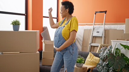 Young pregnant woman smiling confident dancing at new home