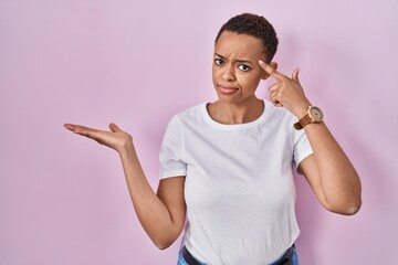 Beautiful african american woman standing over pink background confused and annoyed with open palm...