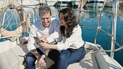 Senior man and woman couple using smartphone sitting together on boat at boat
