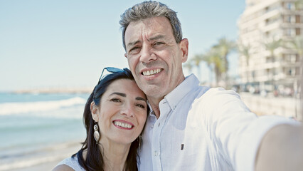 Obraz premium Senior man and woman couple smiling confident make selfie by camera at seaside