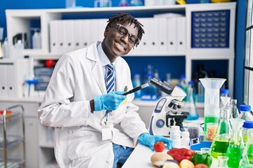 African american man scientist looking tomato using loupe at laboratory