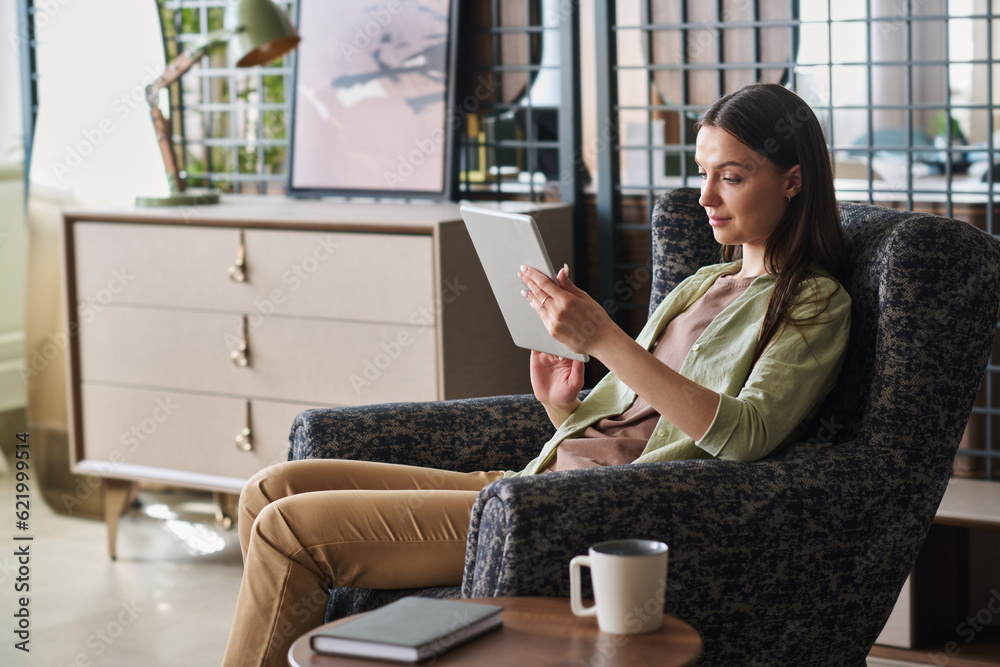 Aufkleber side view of young pretty businesswoman scrolling through online data on tablet screen while sitting