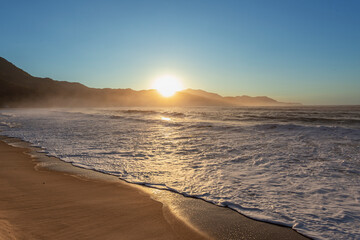 Amanhecer no litoral, sol nascendo atrás da montanha