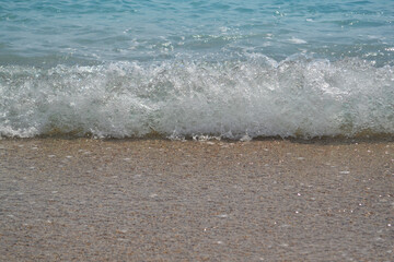 Sea surf on the sunny beach, splashing sea water, summer breeze on the sand bank