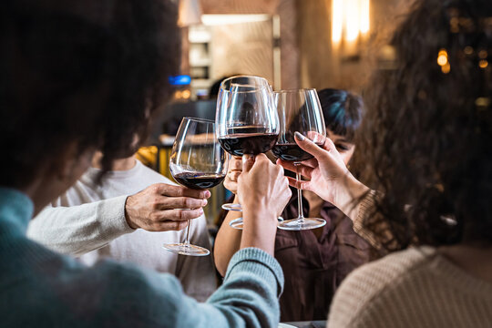 Multicultural Friends Toasting in Elegant Restaurant - Friends raising wine glasses in a toast, captured through a window.