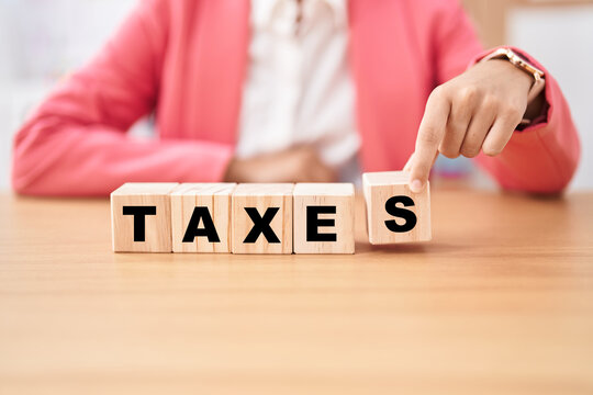 Business woman holding cubes with taxes word on the table