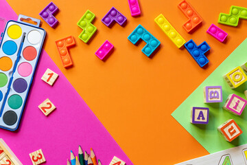 Wooden kids toys on colourful paper. Educational toys blocks, pyramid, pencils, numbers. Toys for kindergarten, preschool or daycare. Copy space for text. Top view	