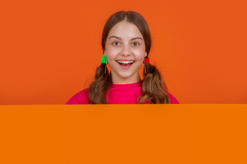 amazed child behind blank orange paper with copy space for advertisement