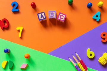 Wooden kids toys on colourful paper. Educational toys blocks, pyramid, pencils, numbers. Toys for kindergarten, preschool or daycare. Copy space for text. Top view	