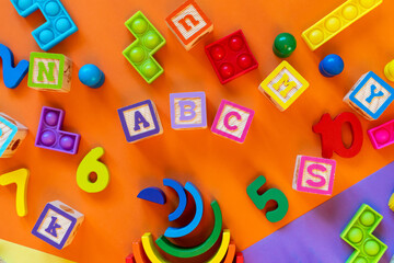 Wooden kids toys on colourful paper. Educational toys blocks, pyramid, pencils, numbers. Toys for kindergarten, preschool or daycare. Copy space for text. Top view	