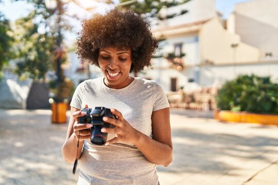 African american woman smiling confident using professional camera at park