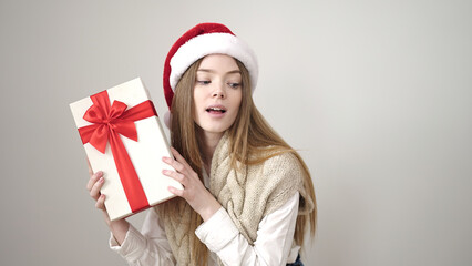 Young blonde woman wearing christmas hat listening gift sound over isolated white background