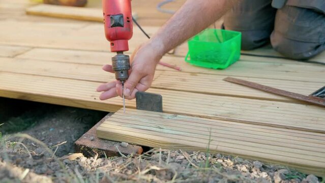 Male builder using drill to screw the screws off the timber	