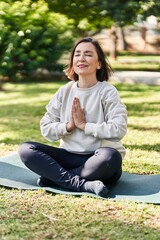 Middle age woman smiling confident training yoga at park