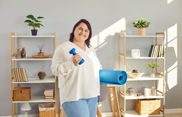 Overweight woman enjoying sports workouts at home. Portrait of happy fat young girl standing in...