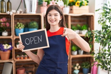 Young caucasian woman working at florist holding open sign pointing finger to one self smiling happy and proud