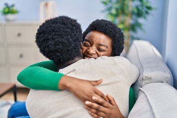 African american man and woman couple hugging each other sitting on sofa at home