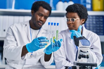 African american man and woman scientists holding test tubes at laboratory