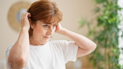 Middle age woman combing hair at bedroom